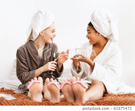 Two young women having spa day together, drinking champagne 61875472