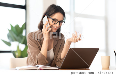 Happy girl talking on the phone at office Happy girl talking on the phone at office 61875483