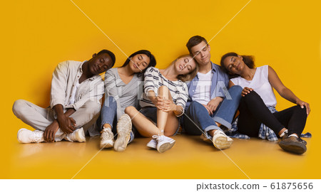 Tired classmates sleeping after exams over yellow background 61875656