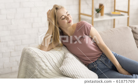Pretty girl relaxing on sofa at home Pretty girl relaxing on sofa at home 61875709