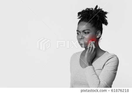 Young black woman touching cheek, feeling pain Young black woman touching cheek, feeling pain 61876218