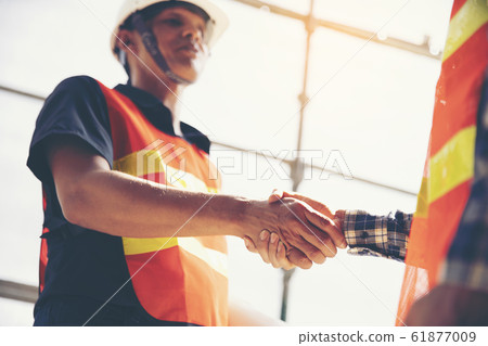 Two construction engineers shake hands in Two construction engineers shake hands in 61877009