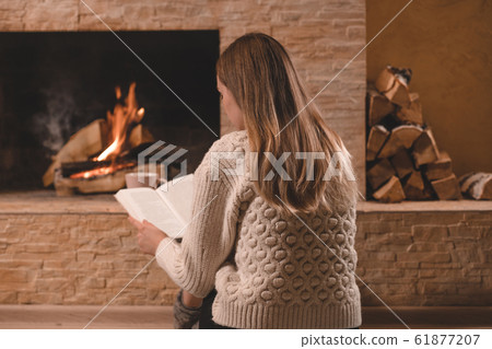 Girl reading book near by the fireplace Girl reading book near by the fireplace 61877207