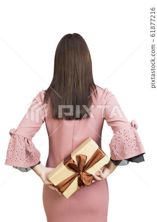 Girl holds a gift behind her back. Girl holds a gift behind her back. 61877216