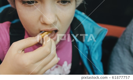 Child eat pizza and french fry potato. Close up of young girl woman eating pizza and chewing in outdoor restaurant. 61877757