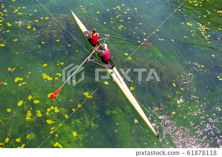 Two young athletes rowing team on green lake 61878118