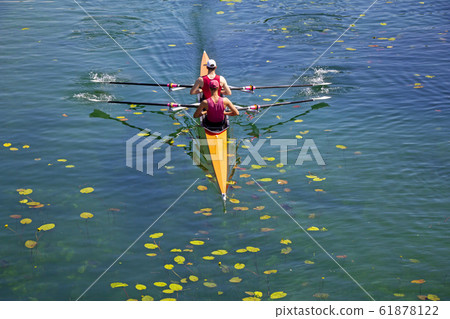 Two young athletes rowing team on green lake Two young athletes rowing team on green lake 61878122