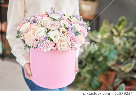 European floral shop. Floral bunch in round box. Bouquet of beautiful Mixed flowers in woman hand. Excellent garden flowers in the arrangement , the work of a professional florist. European floral shop. Floral bunch in round box. Bouquet of beautiful Mixed flowers in woman hand. Excellent garden flowers in the arrangement , the work of a professional florist. 61879224