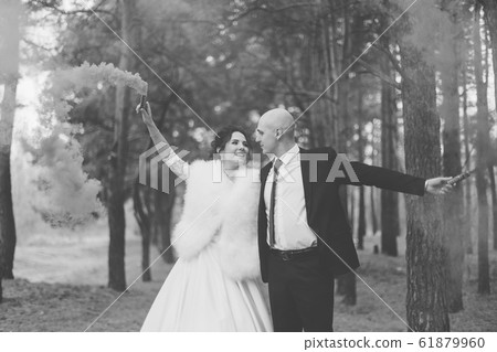 Happy bride and groom hold colored smoke in their 61879960