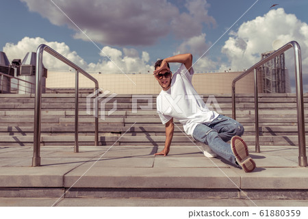 dancer is young guy, in summer in city, dancing street dances, break movement, modern youth style. Fashion and fitness sport. Free space for copy text. 61880359