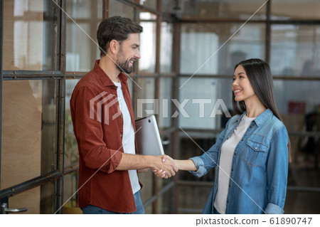 Young girl in jeans jacket giving hand to her colleague 61890747