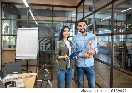 Two colleagues standing in the office together and looking determined Two colleagues standing in the office together and looking determined 61890914