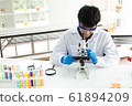 Science, Chemistry, Technology, Biology and Laboratory concept - Asian junior scientist is looking for something through a microscope in his laboratory. 61894209