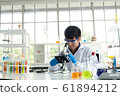 Science, Chemistry, Technology, Biology and Laboratory concept - Asian junior scientist is looking for something through a microscope on his table to be full of experimental equipment in laboratory. 61894212
