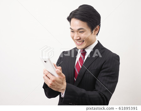 Businessman rejoicing looking at smartphone screen Businessman rejoicing looking at smartphone screen 61895391