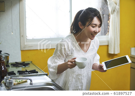 Portrait of young woman standing in the kitchen 61897527
