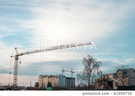 Yellow high tower cranes building house at sunset 61899758