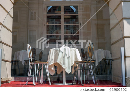 Table covered with white tablecloth and chairs on Table covered with white tablecloth and chairs on 61900502