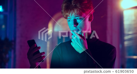 Cinematic portrait of handsome young man in neon lighted interior Cinematic portrait of handsome young man in neon lighted interior 61903650