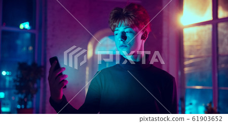 Cinematic portrait of handsome young man in neon lighted interior Cinematic portrait of handsome young man in neon lighted interior 61903652