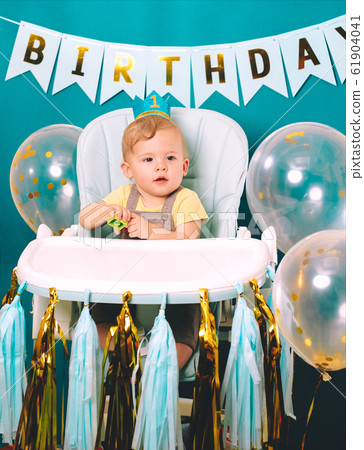 Cute baby boy sitting in his chair and playing with colorful bricks. Birthday handsome toddler child with big eyes portrait. Funny kid. 61904041