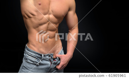Cropped photo of a sporty man with a muscular body in unbutton shirt and jeans posing in studio. Cropped photo of a sporty man with a muscular body in unbutton shirt and jeans posing in studio. 61905961
