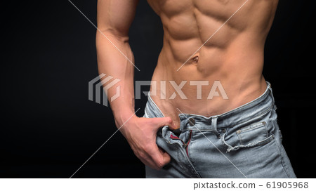 Man in blue jeans with a perfect abs showing his muscular body Man in blue jeans with a perfect abs showing his muscular body 61905968