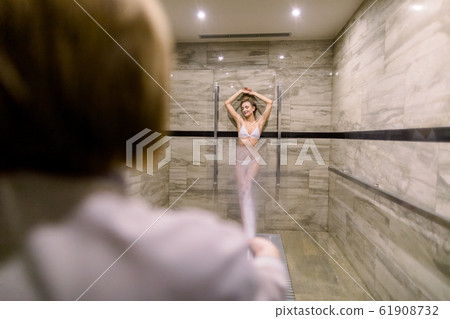 Young woman having high pressure shower after the treatment wrapping procedure at the modern spa salon. Concept of hydrotherapy and Sharko shower Young woman having high pressure shower after the treatment wrapping procedure at the modern spa salon. Concept of hydrotherapy and Sharko shower 61908732