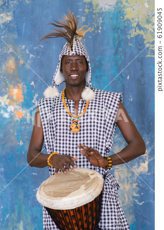 African artist in traditional clothes playing djembe drum African artist in traditional clothes playing djembe drum 61909045