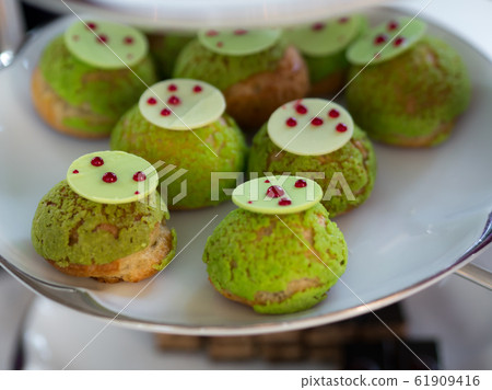 Tasty Mini Green Tea Choux au Craquelin or French Crunchy Cream Puff filled with delicious and creamy Chantilly Cream on white plate. Tasty Mini Green Tea Choux au Craquelin or French Crunchy Cream Puff filled with delicious and creamy Chantilly Cream on white plate. 61909416