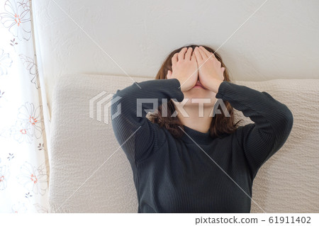 一個女人坐在沙發上疲憊不堪 一個女人坐在沙發上疲憊不堪 61911402