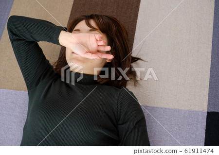 Woman lying down in living room fatigue break 61911474
