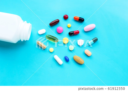 Colorful tablets with capsules and pills on blue 61912350