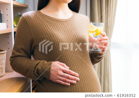 Pregnant woman drinking carbonated water lemon Pregnant woman drinking carbonated water lemon 61916352