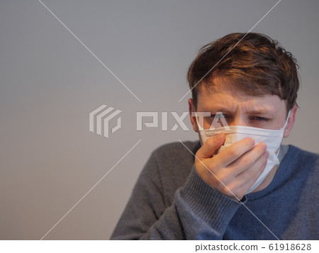 A handsome young man wearing a mask with the flu 61918628