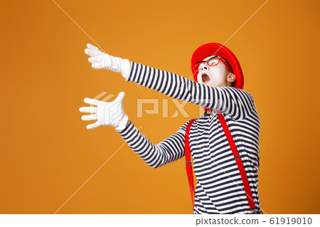 Sad mime in red hat and vest on orange background 61919010