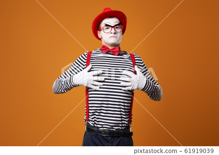 Mime man in vest and red hat on orange background Mime man in vest and red hat on orange background 61919039