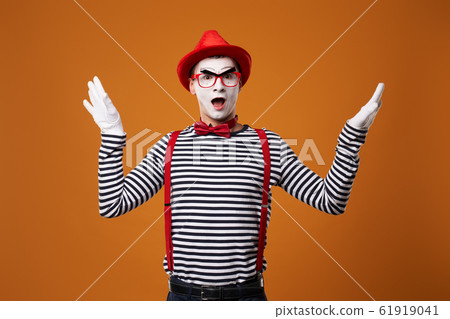 Surprised mime in red hat and vest showing thumb up on orange background Surprised mime in red hat and vest showing thumb up on orange background 61919041