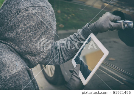 Hooded thief tries to break the car's security 61921496