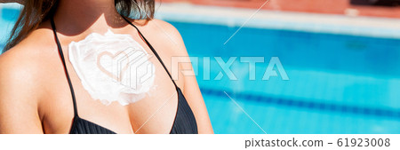 Heart shape sunscreen on woman's breast by the Heart shape sunscreen on woman's breast by the 61923008