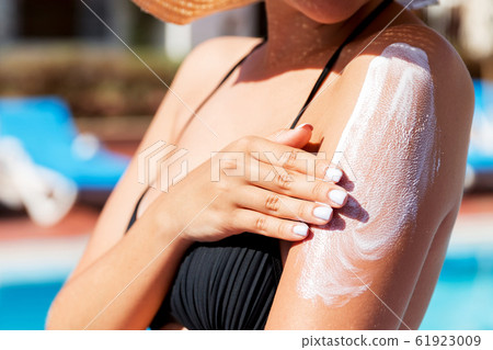 Pretty woman applying sun cream with her hands on Pretty woman applying sun cream with her hands on 61923009