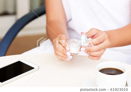 Cropped image of female hands applying cream at 61923010