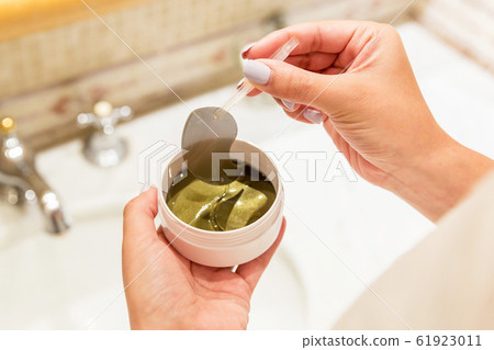 Female hands are taking eye patches out from the Female hands are taking eye patches out from the 61923011