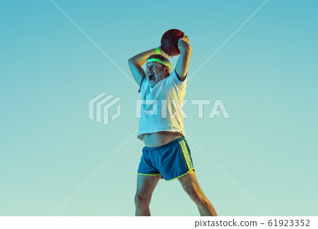 Senior man playing basketball in sportwear on gradient background and neon light Senior man playing basketball in sportwear on gradient background and neon light 61923352
