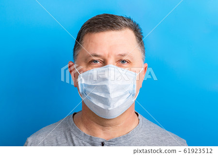 Portrait of man wearing medical mask at blue 61923512