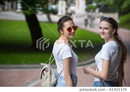 Two young women walking in summer in the Park. Two young women walking in summer in the Park. 61925376