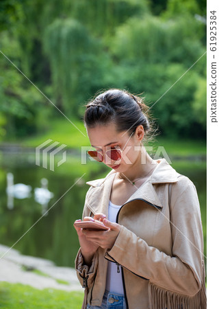 Girl on the street looks at the phone on nature 61925384