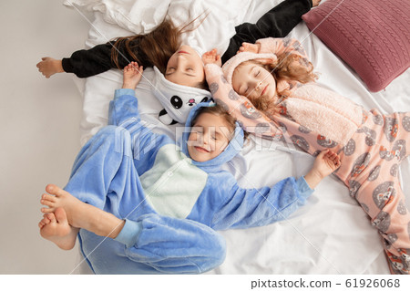 Children in soft warm pajamas having party colored bright playing at home Children in soft warm pajamas having party colored bright playing at home 61926068