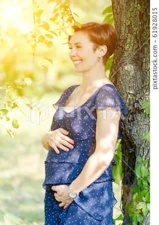 Pregnant Mid-Aged Woman Happily Laughs In The Park Gently Touching Her Tummy Pregnant Mid-Aged Woman Happily Laughs In The Park Gently Touching Her Tummy 61928015