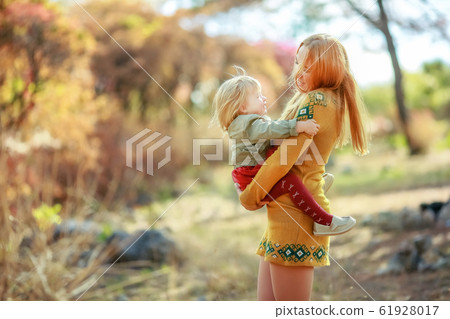A woman with a child in her arms amuses the girl and spins with her in different directions A woman with a child in her arms amuses the girl and spins with her in different directions 61928017